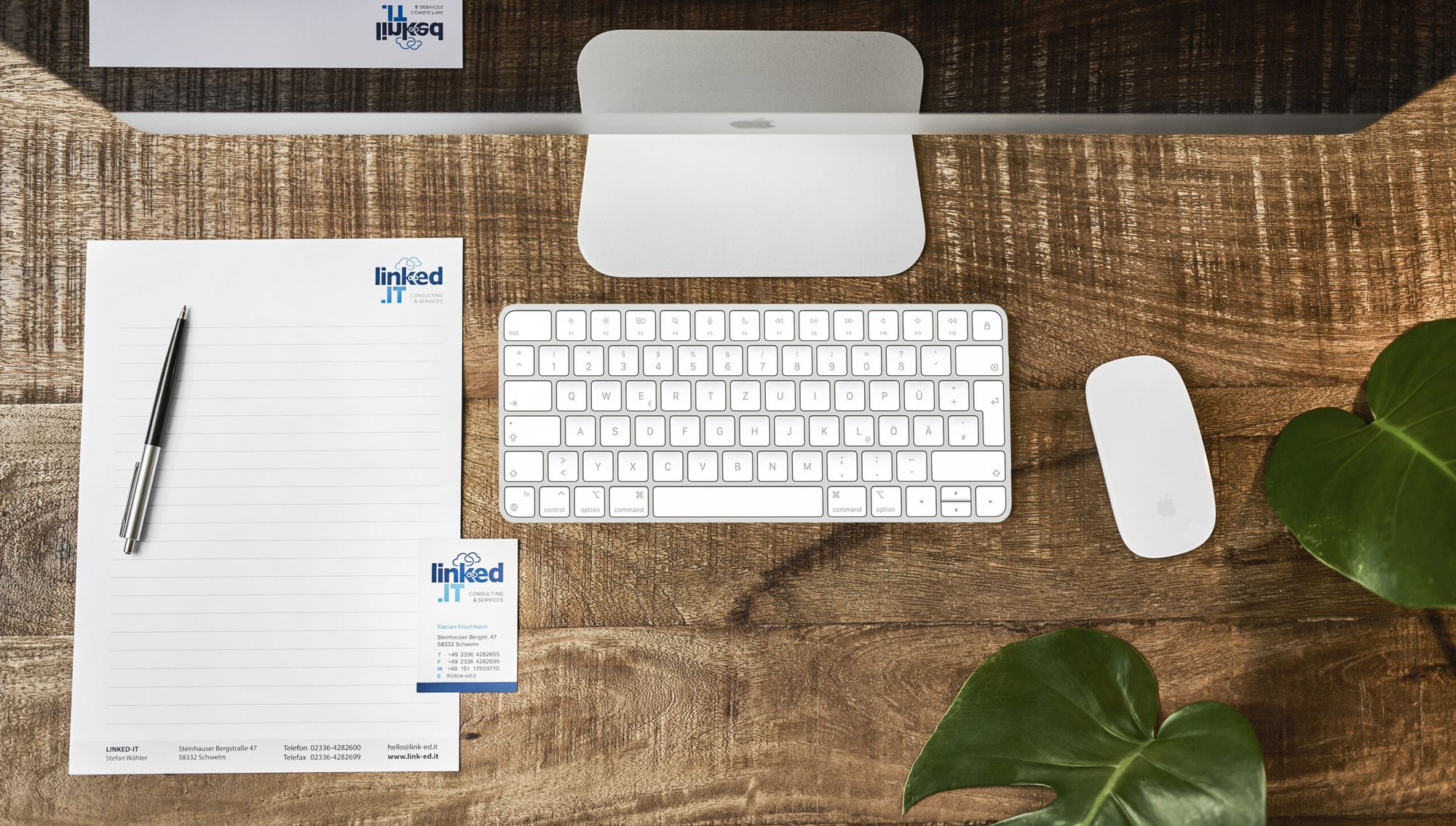 Aufgeräumter Arbeitsplatz mit Computer, Tastatur und Briefpapier von link-ed.it